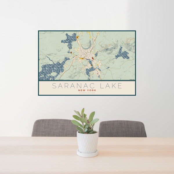 24x36 Saranac Lake New York Map Print Lanscape Orientation in Woodblock Style Behind 2 Chairs Table and Potted Plant